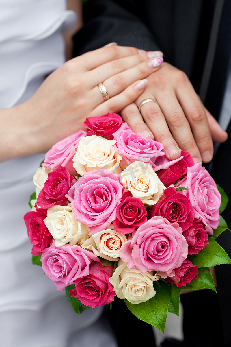 新娘和新郎的手放在新娘捧花上图片
