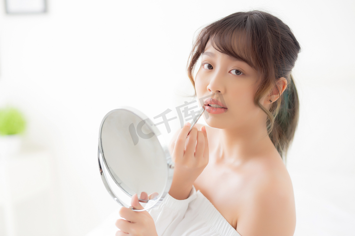 美丽的肖像年轻亚洲女人看着镜子应用 mak图片