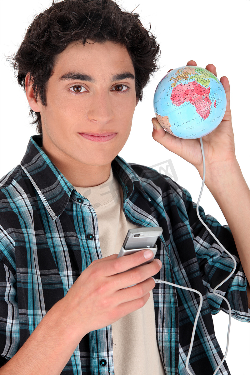 一个十几岁的男孩拿着一个连接到地球仪的手机图片
