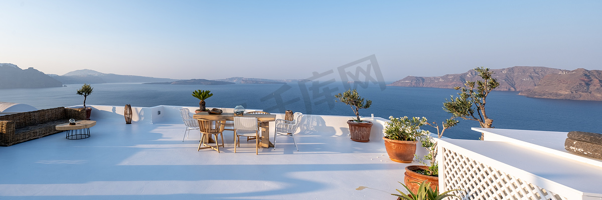希腊圣托里尼海边一家餐厅的户外露台，海边的椅子和桌子上放着鲜花图片