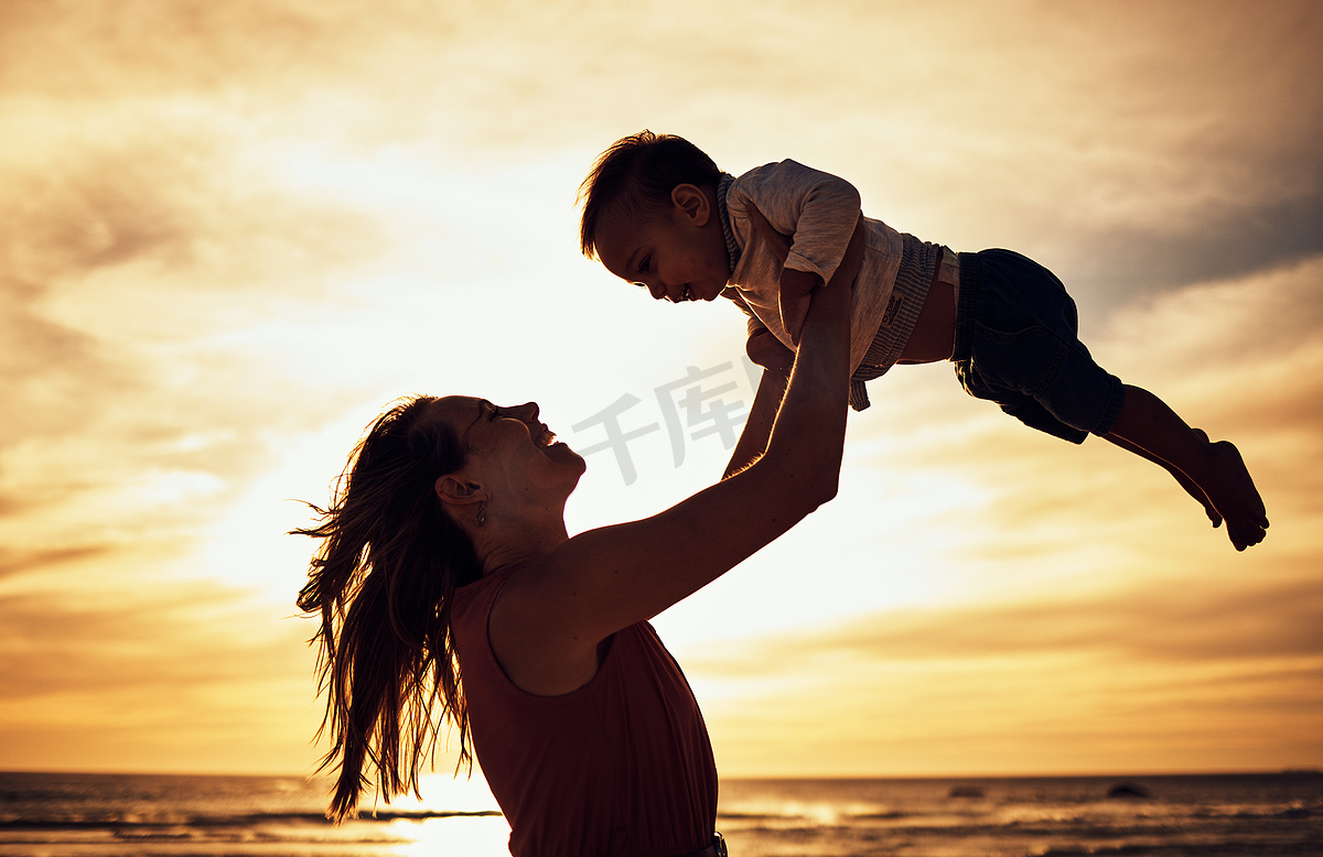 家庭、剪影和海滩日落与母亲和婴儿在金色天空的衬托下在夏季度假时充满爱、关怀和支持。图片