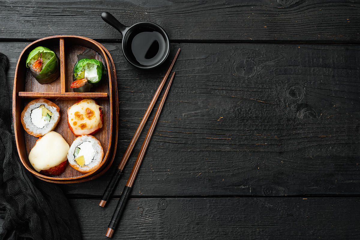 带筷子的日式便当午餐盒，黑色木桌背景，顶视图平躺，带复制空间和文本空间图片