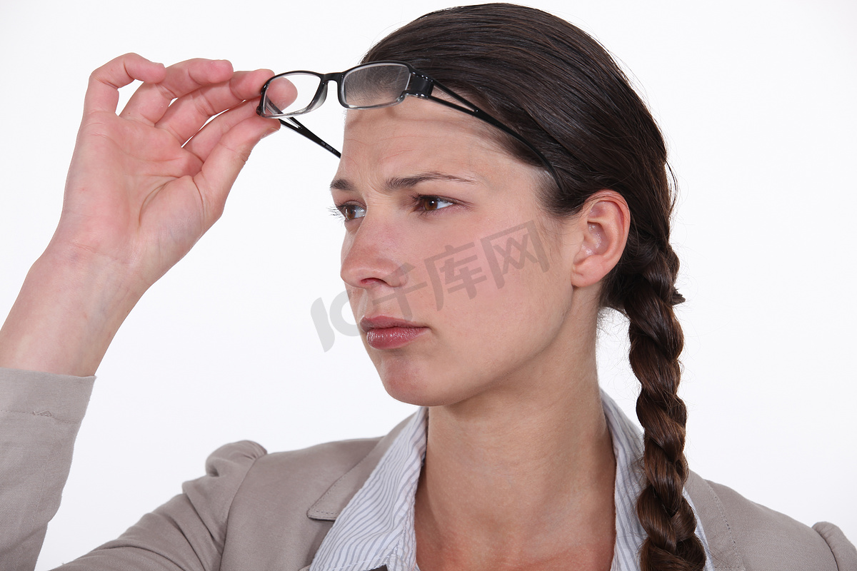 困惑的女人摘下眼镜以便更好地看东西图片