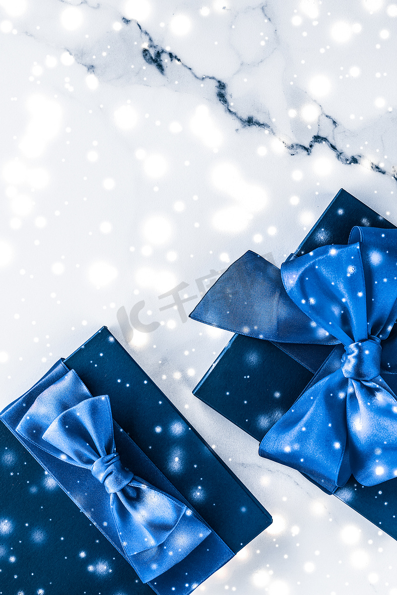 冬季节日礼盒，配有蓝色丝绸蝴蝶结、大理石背景上的雪花，作为豪华美容品牌的圣诞和新年礼物，平铺设计图片