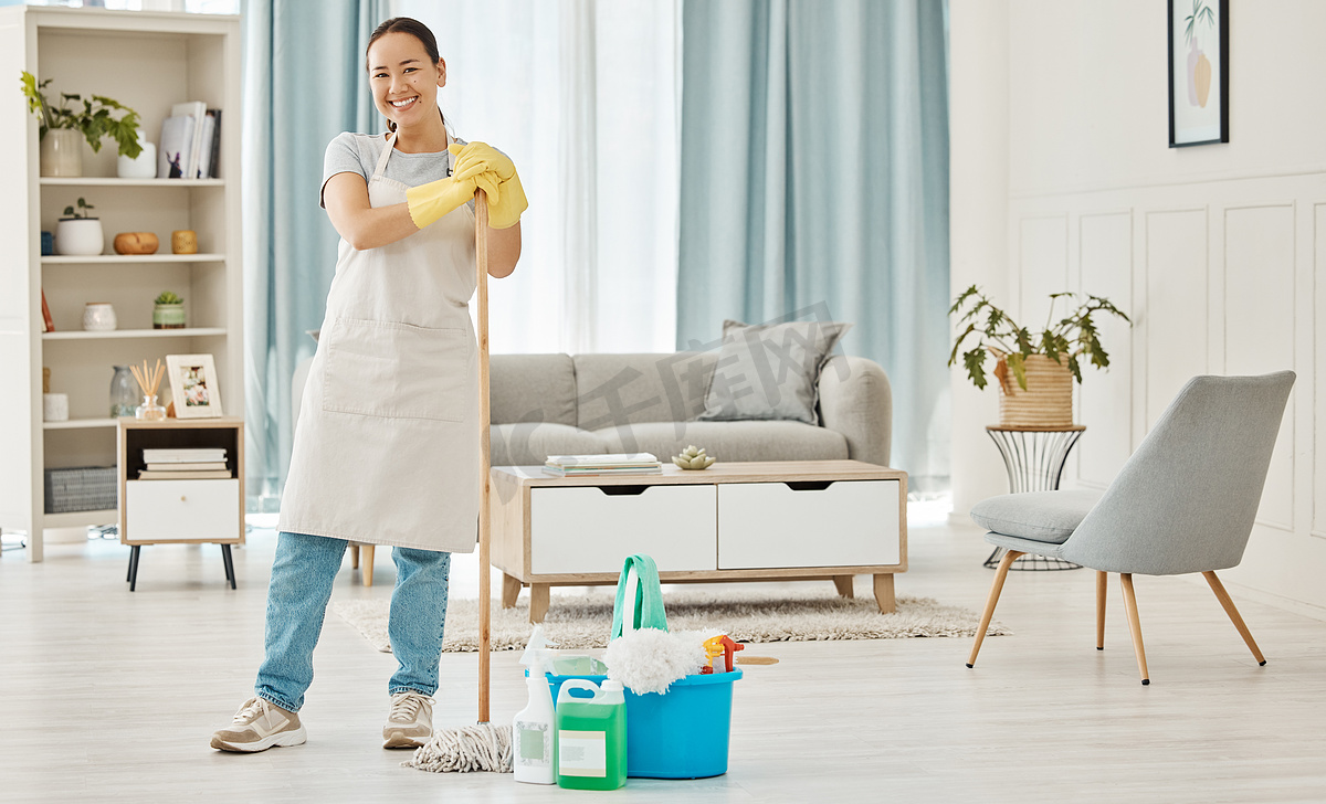 快乐的女人清洁家庭地板，做家务，在家政服务中微笑，拖地客厅，戴着手套工作，并快乐地打扫房屋公寓。图片