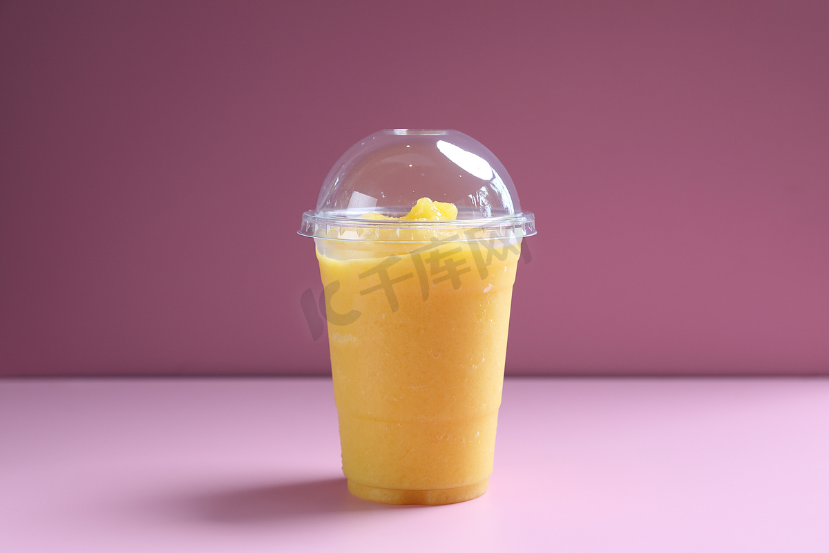 芒果冰沙奶昔，带粉色背景中隔离的玻璃杯图片