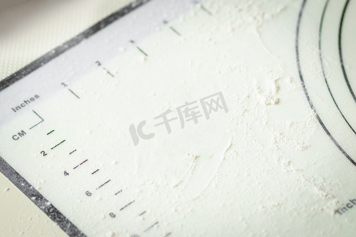 白色硅胶烹饪垫，上面有厘米和英寸标记，上面撒有面粉，复制空间图片