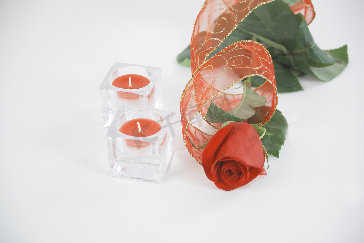 白色背景上的两支蜡烛和一朵红玫瑰。带副本的照片图片
