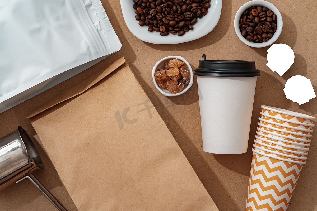 带咖啡豆和纸杯的空白棕色牛皮纸袋，适合您的设计图片