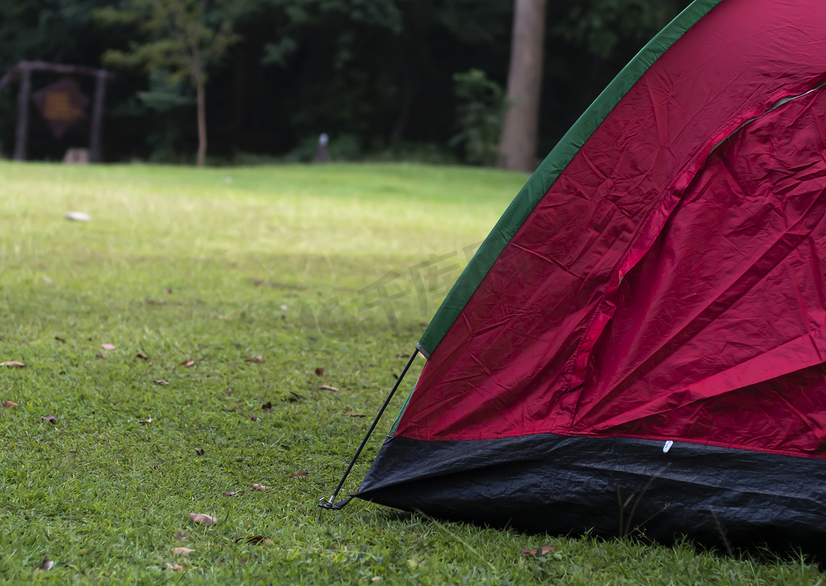 假期周末在田野绿草森林背景上的红色露营帐篷。图片