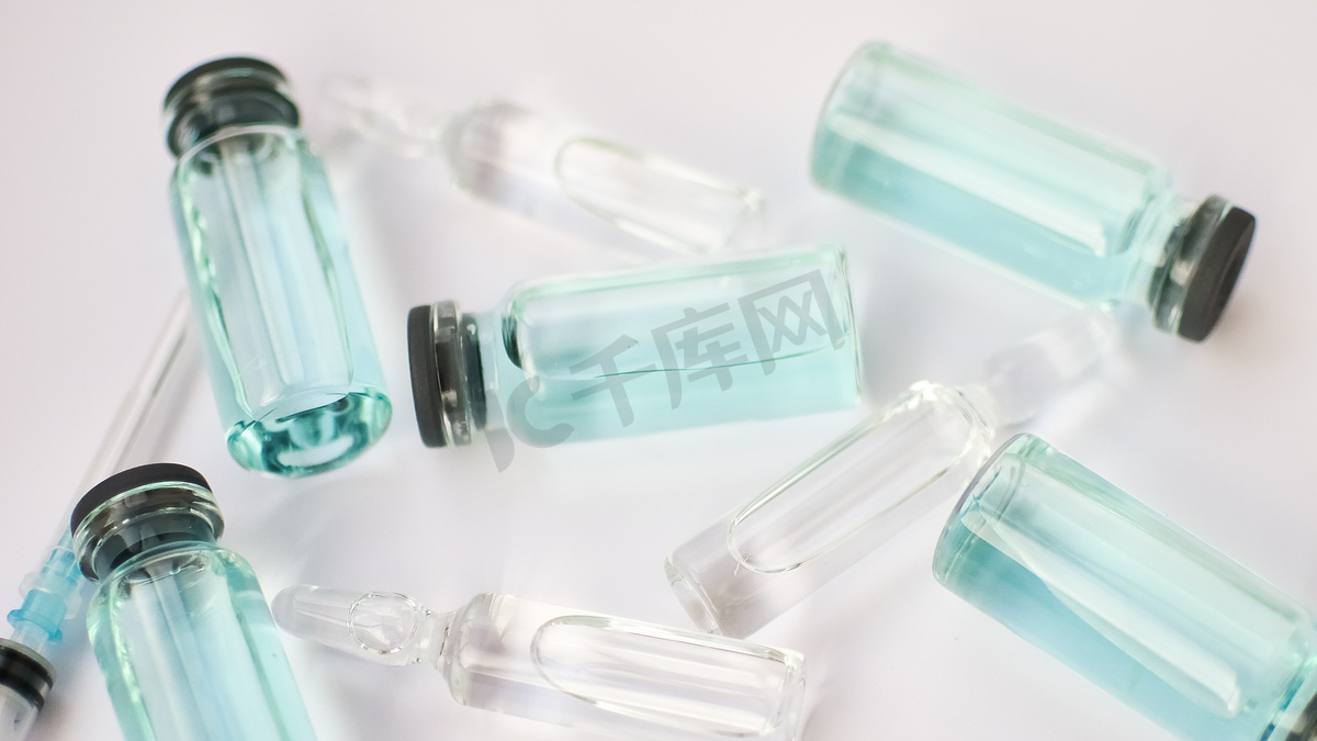 小瓶疫苗，白色背景上透明和蓝色液体的玻璃安瓿顶视图，全球疫苗接种概念图片
