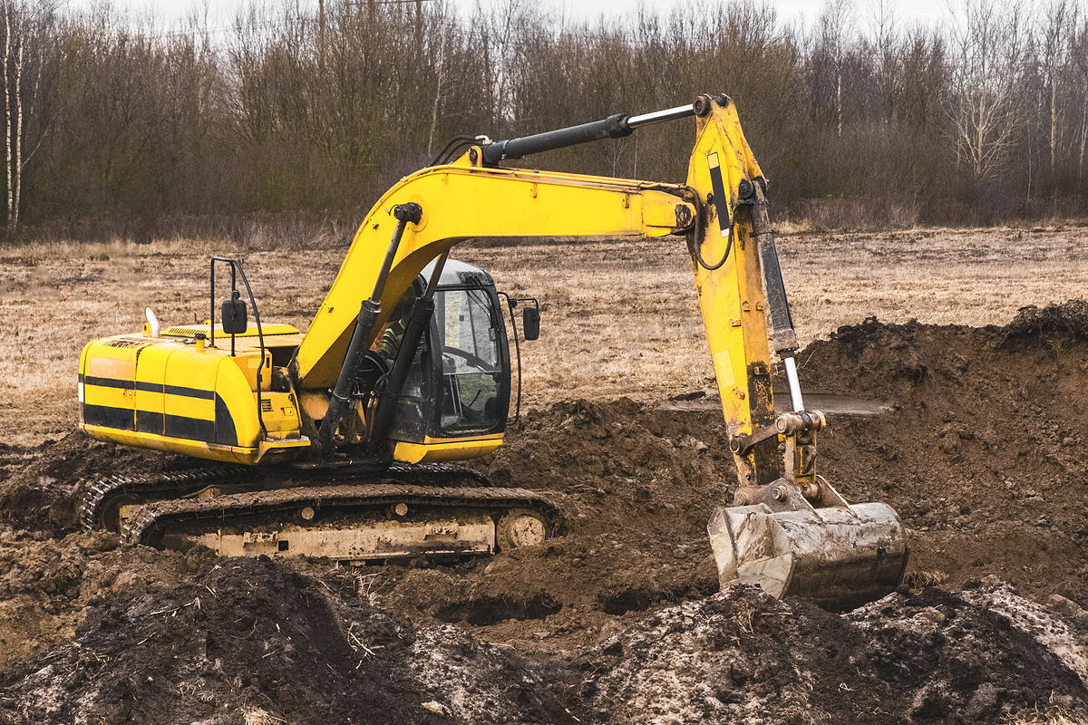 履带式挖掘机设备上的建筑工人在工业区挖沟。图片