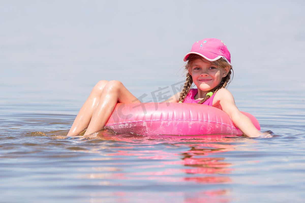 戴帽子的女孩在河里游泳，坐在腿上游泳，看着画面图片