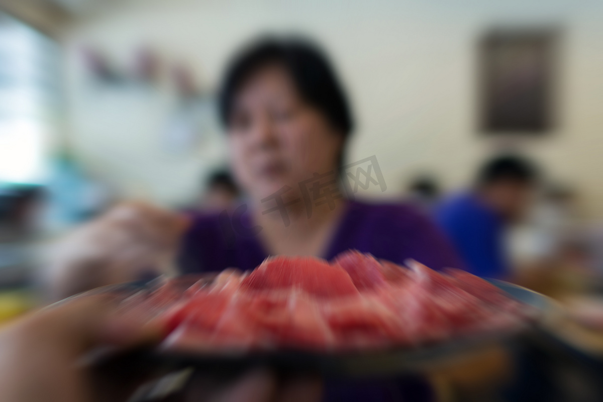 亚洲妇女将肉牛肉放入火锅中烹饪图片
