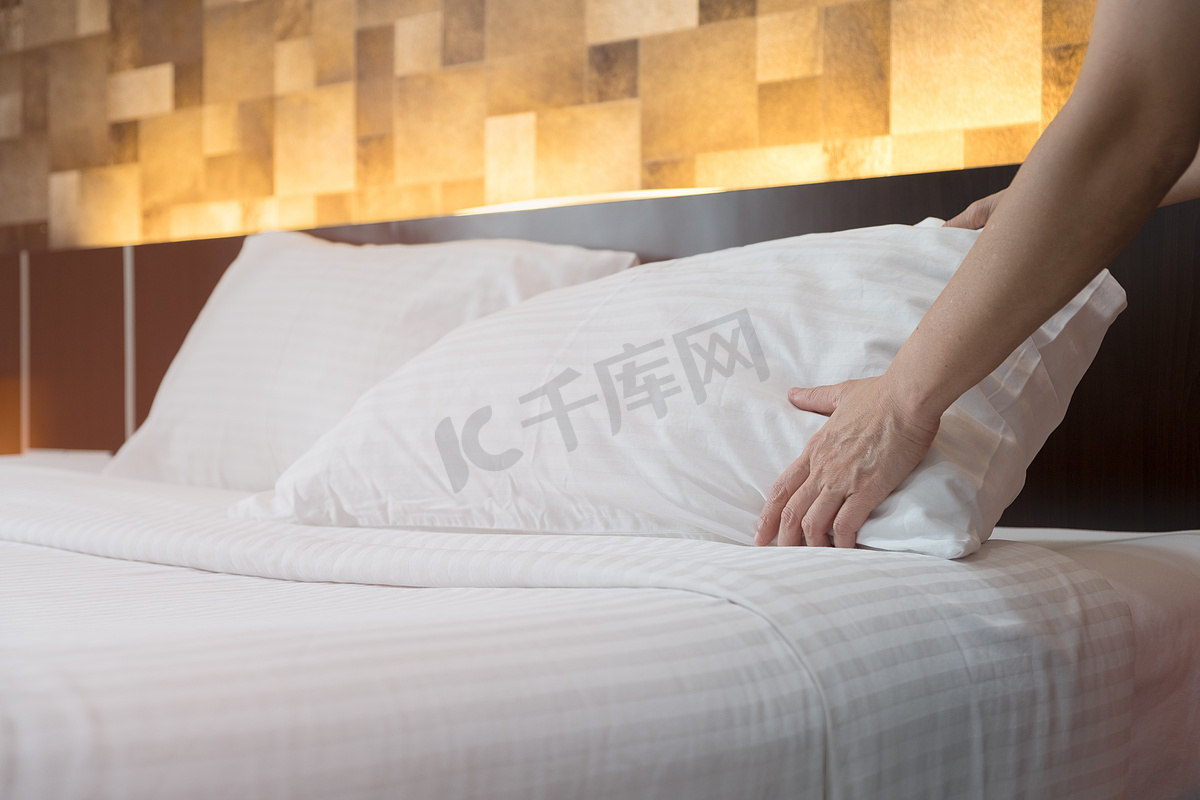 酒店客房服务手在 h 的床上设置了白色枕头图片