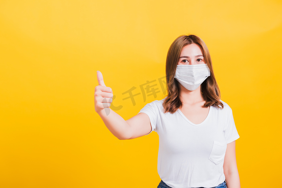 戴口罩保护的妇女，显示拇指手指很好地阻止了病毒爆发控制图片