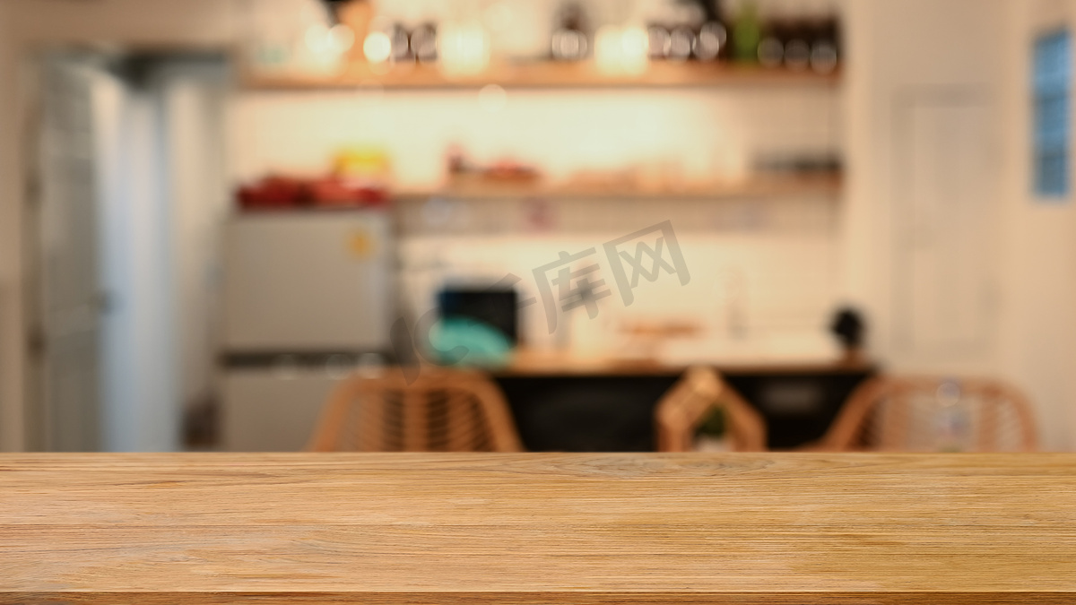 木桌反对背景中模糊的现代厨房。图片