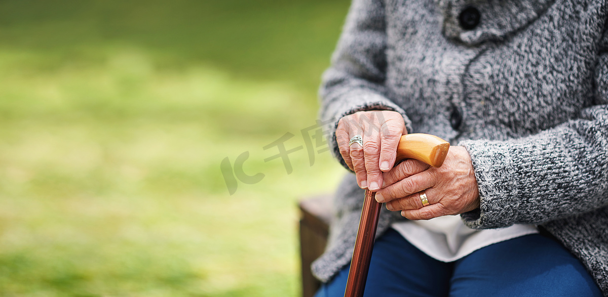 老妇人、手和拐杖在公园长椅上或退休时的大自然。图片