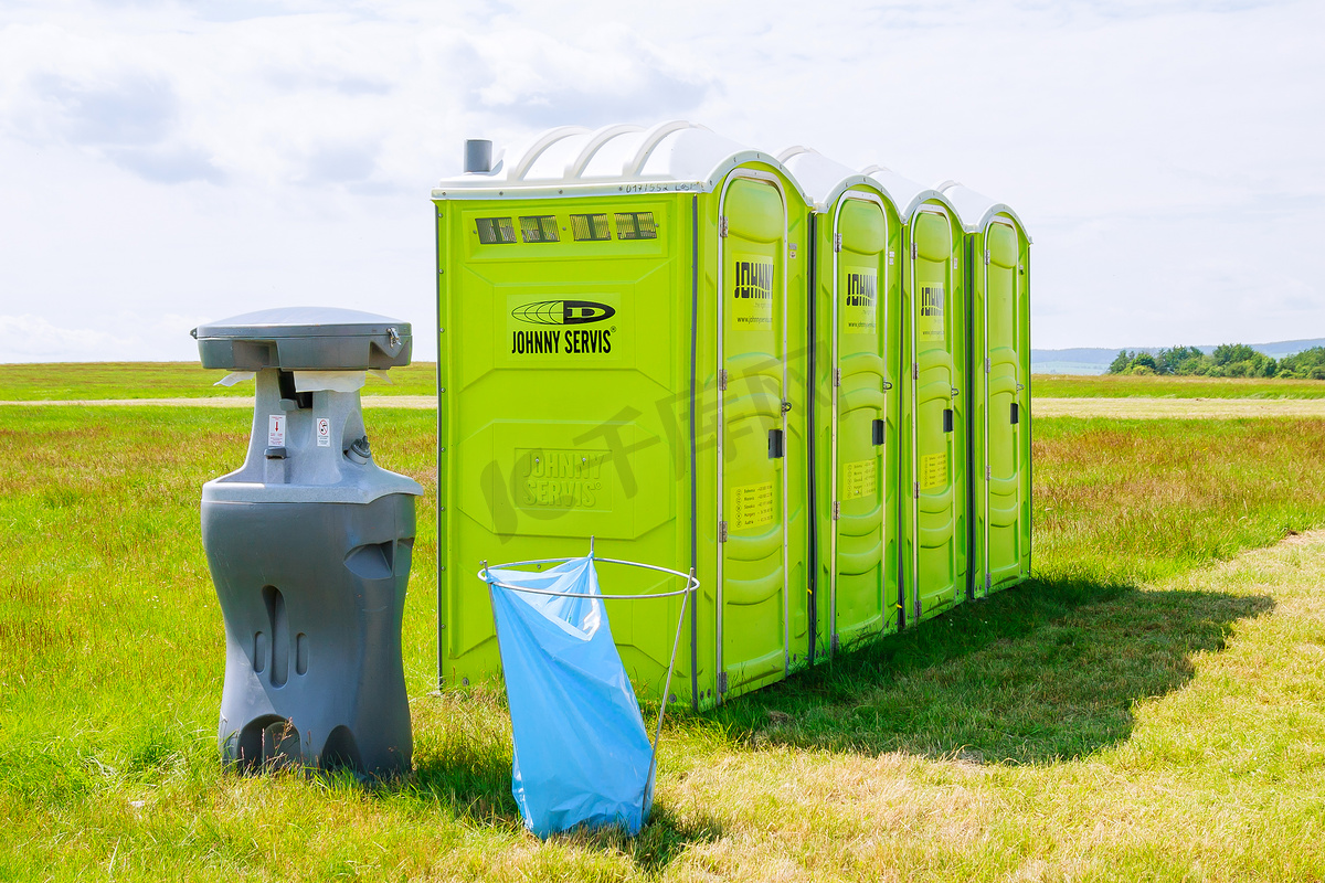 捷克共和国斯库泰克，2020年6月26日：云背景草地上的便携式厕所。图片