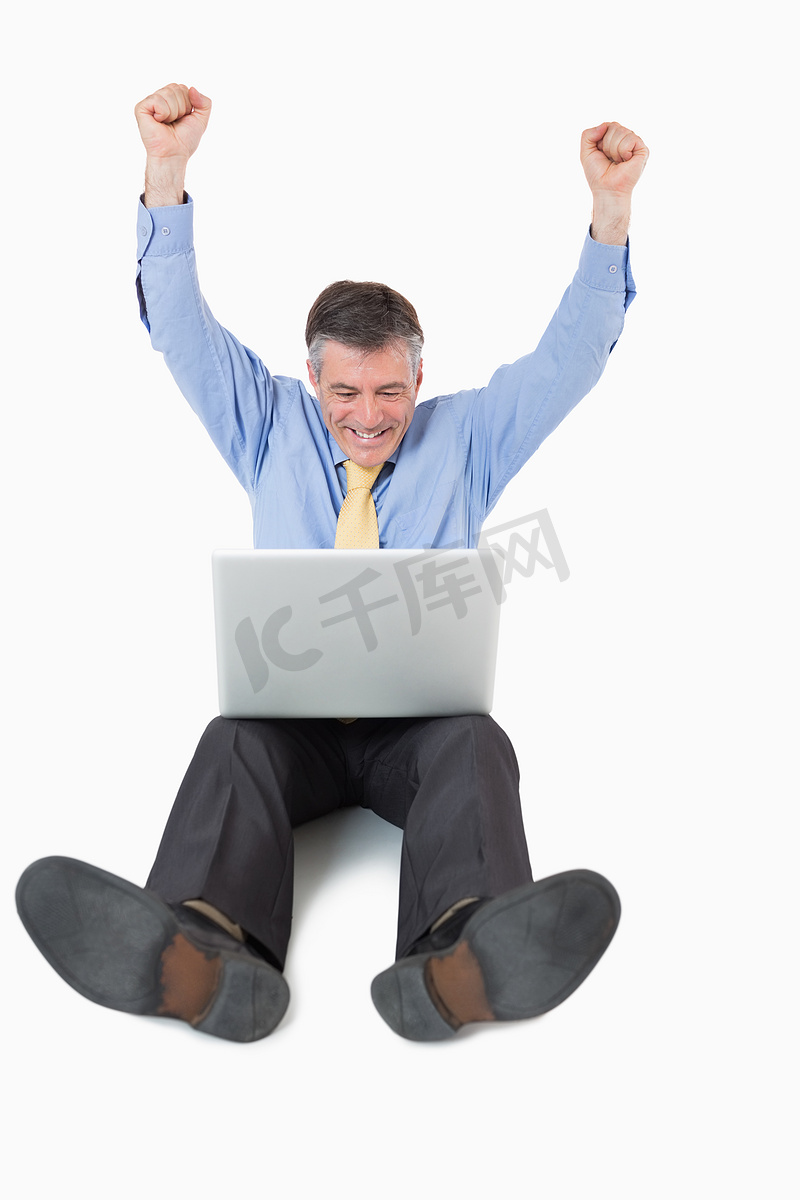 成功的男人带着他的笔记本电脑躺在地板上图片