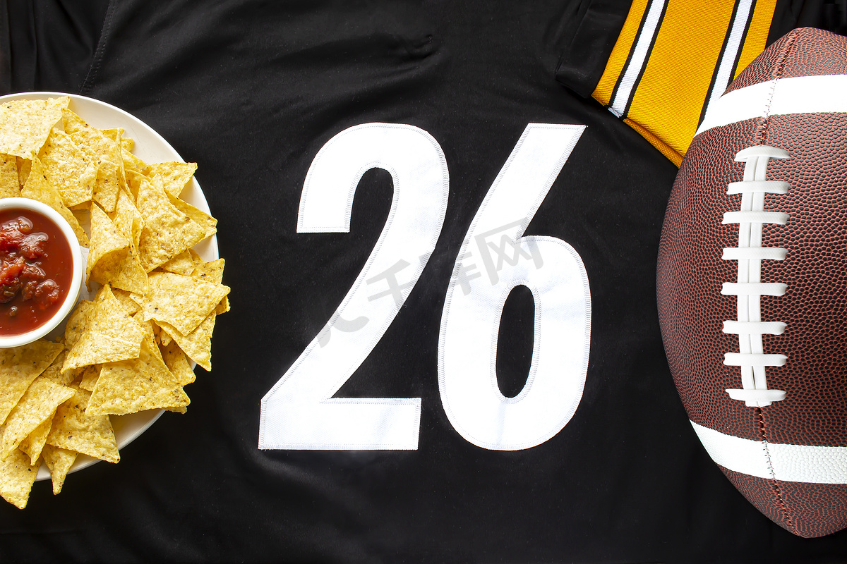 白色黑色足球球衣上配有有机玉米片和温和莎莎酱的美式足球，水平视图上有 26 号图片