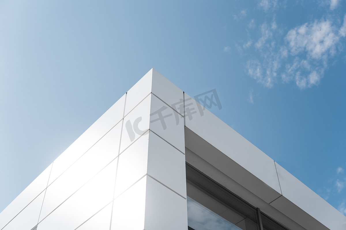 建筑采用白色铝制外墙和铝板，映衬蓝天。图片