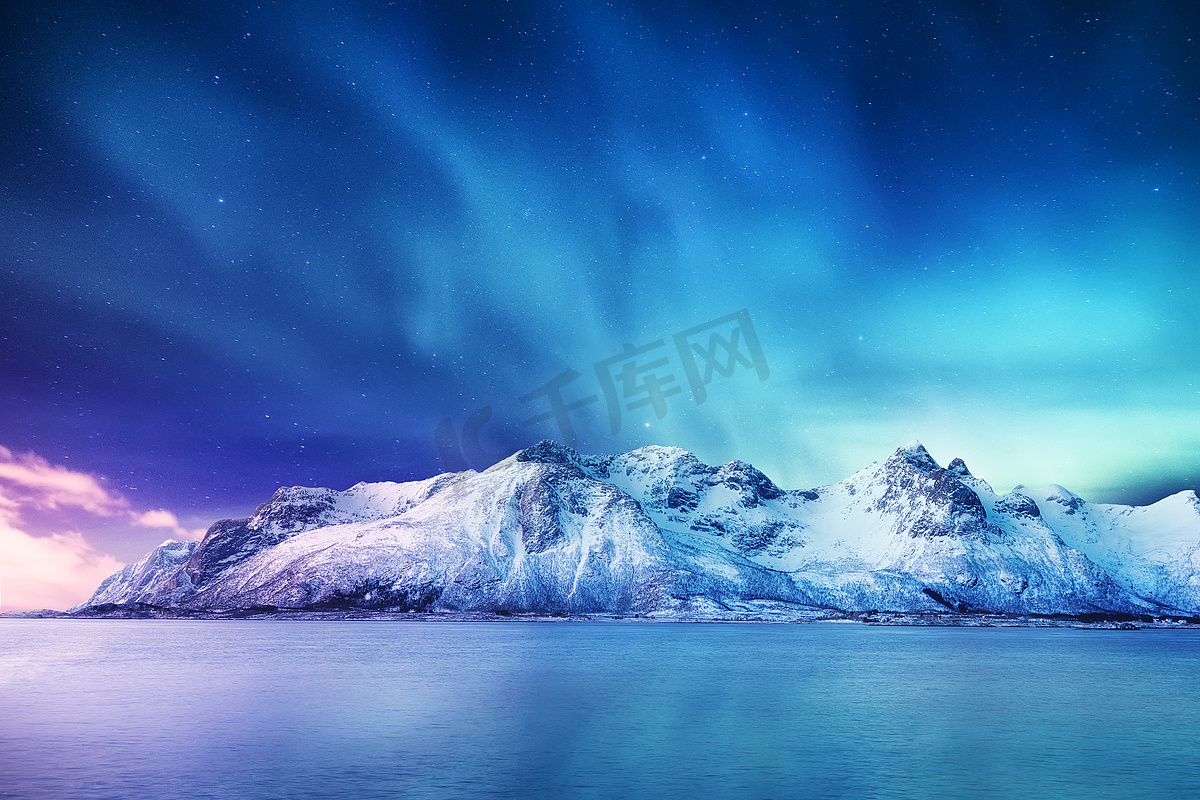挪威洛福敦群岛上的北极光。山上绿色的北极光。夜间冬季景观与极光和反射的水面上。诺威形象图片