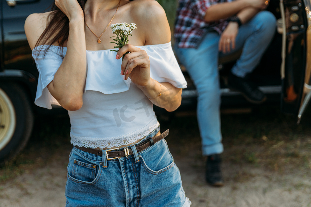 一个拿着花、穿着白色衬衫的女孩, 一个穿格子衬衫的男人坐在汽车座椅的后座上等着图片