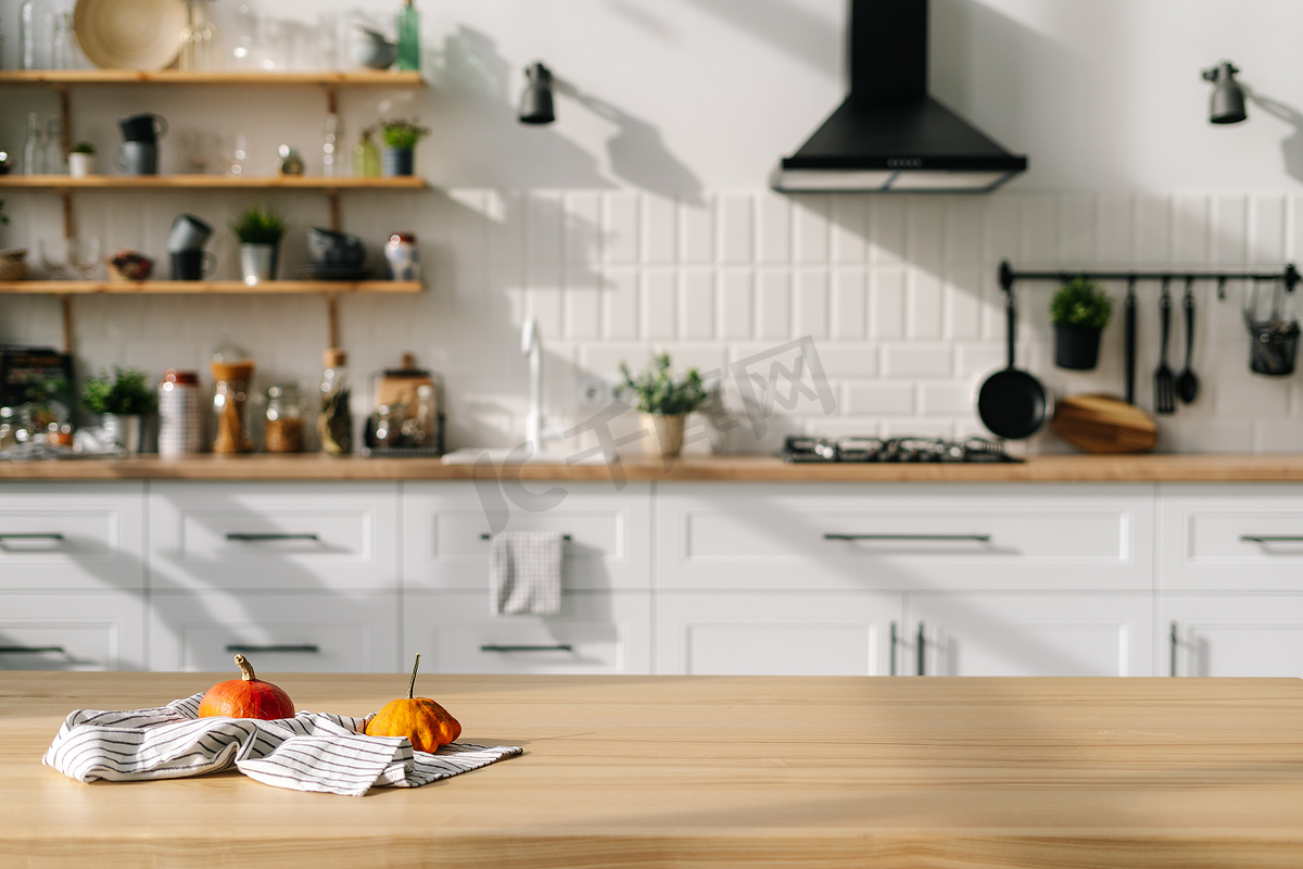 现代风格厨房室内设计与小南瓜毛巾。背景上的当代白色家具、餐具、植物、器具和装饰图片