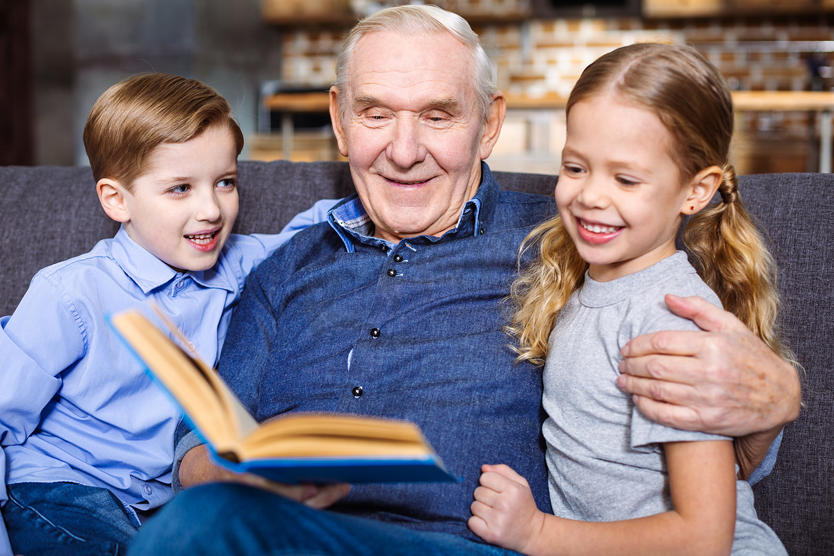 分享你的智慧。积极的老人在家休息时为孙子们读书图片