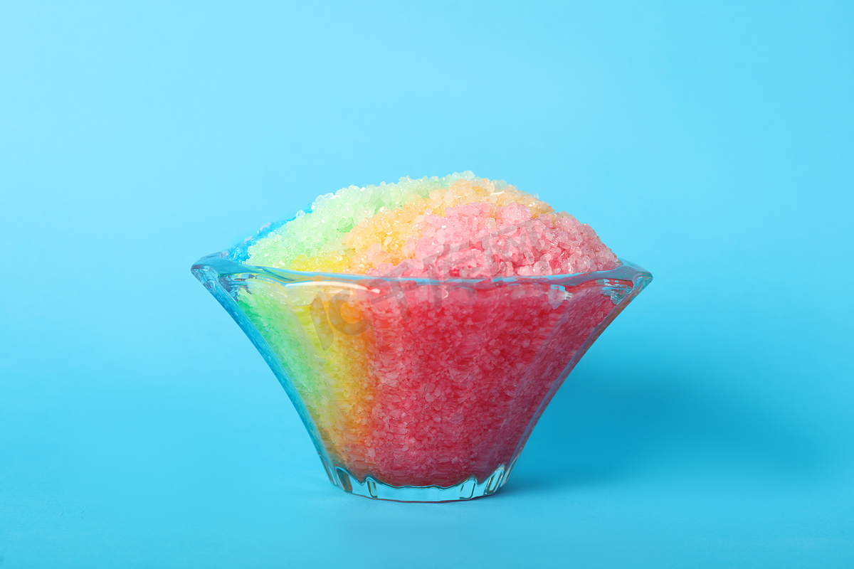 浅蓝色底色玻璃甜点碗中的彩虹刨冰图片