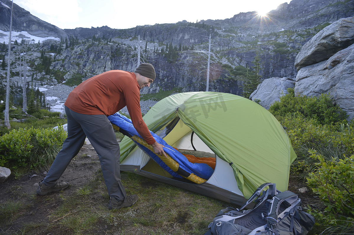 日落时分爱达荷州塞尔柯克山脉的故障湖上一名男子将睡袋放在帐篷里图片