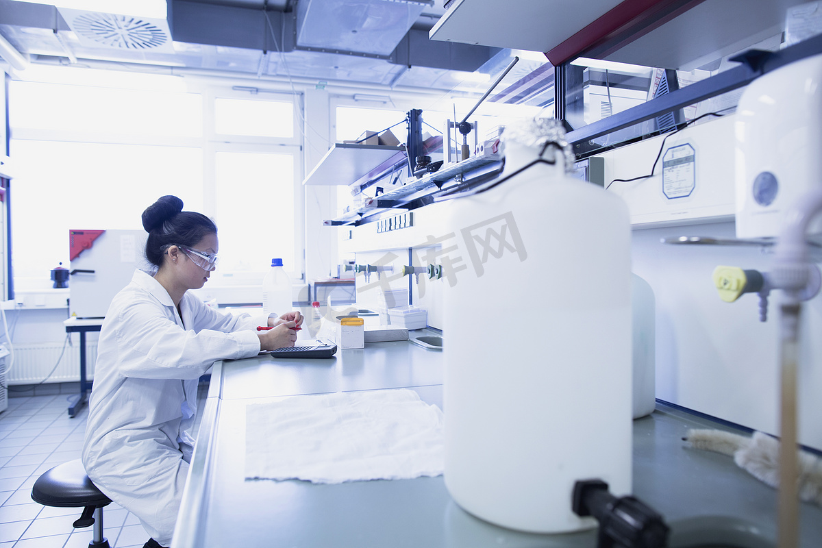 年轻女科学家在实验室工作台上沉思研究笔记图片
