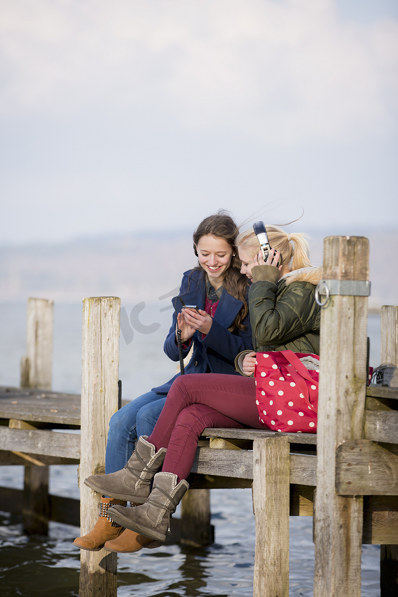 十几岁的女孩坐在码头上听音乐图片