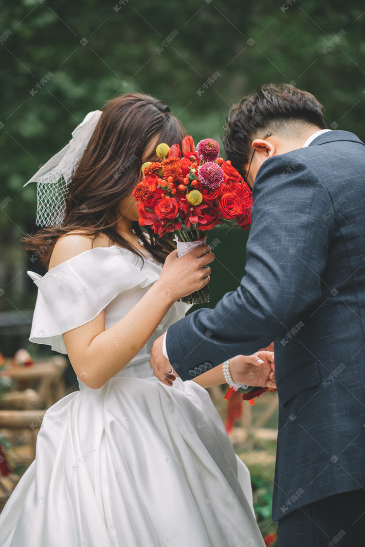 婚礼白天在婚礼现场的新郎新娘户外草坪整理服装摄影图配图
