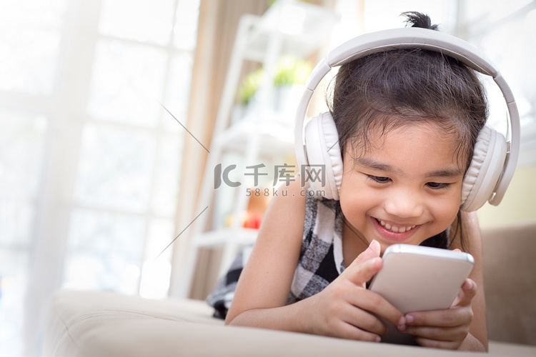 快乐的亚洲女孩使用耳机听音乐的