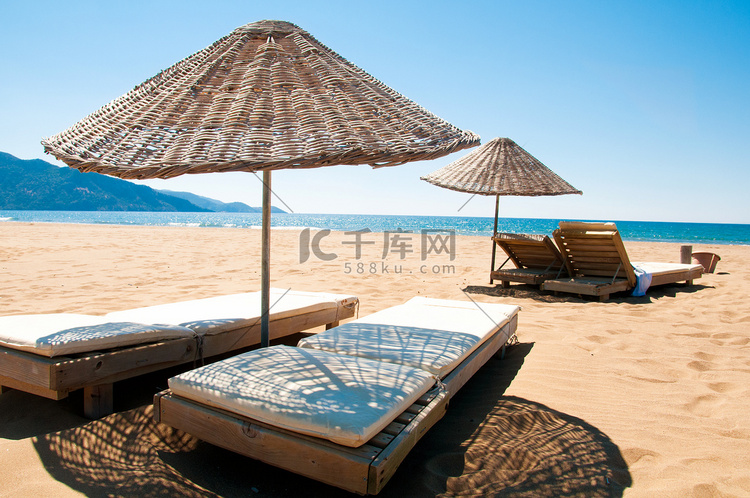 在沙海边的日光浴浴床和藤遮阳伞