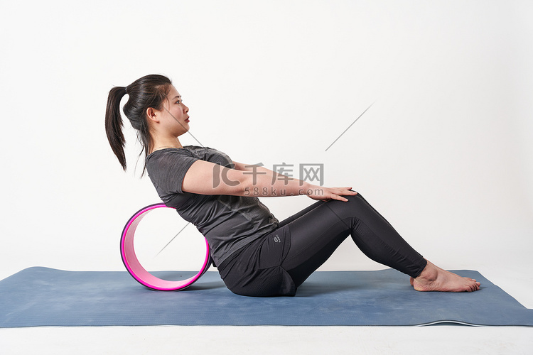 减肥瑜伽胖女人背靠瑜伽轮双手放