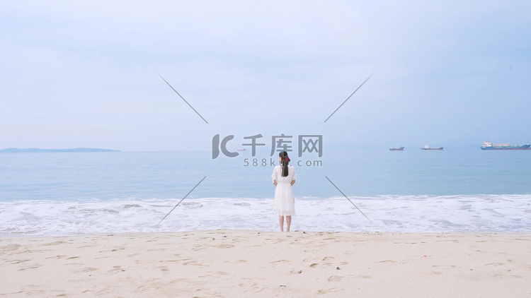 站在海滩上的白衣少女看向大海