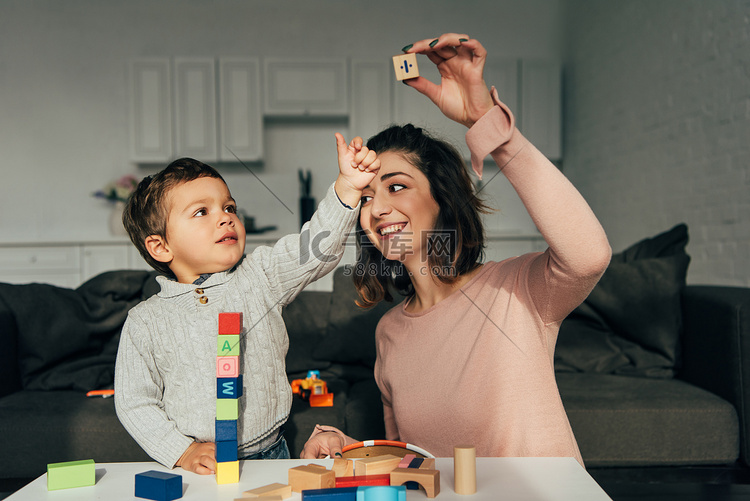 孩子和他的母亲玩块木塔游戏在家