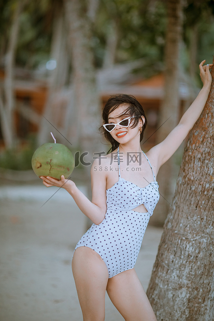 人物午后美女沙滩手拿椰子摄影图