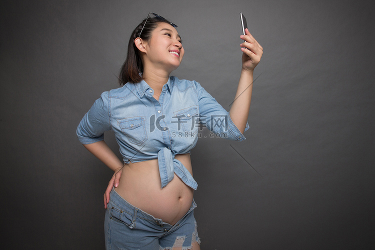 穿着时尚的孕妇拿着手机