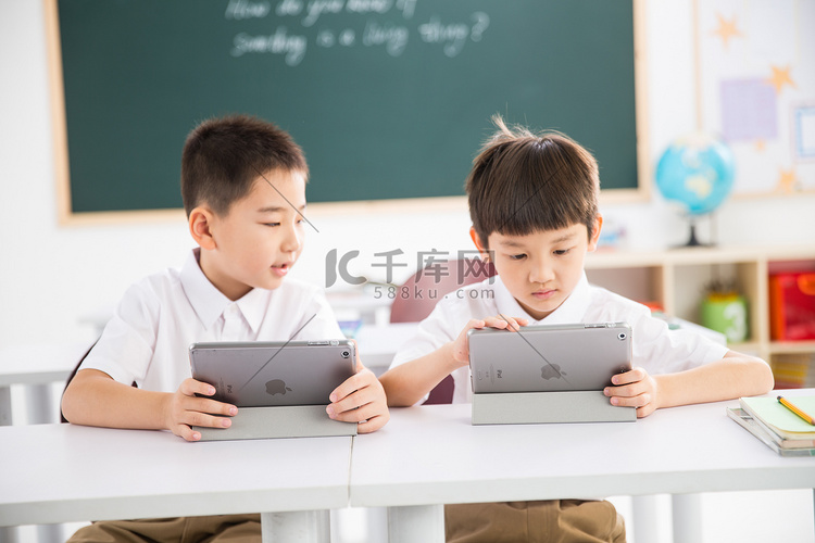 两个小学生在使用平板电脑