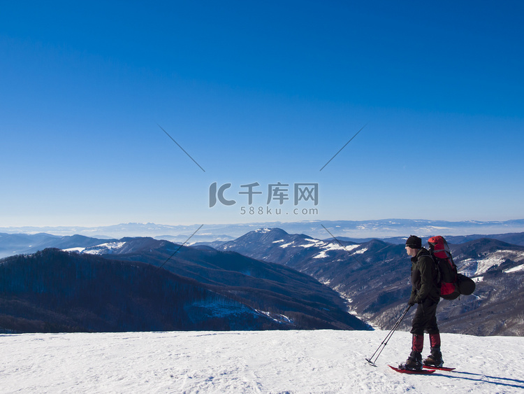 靴子和背包的人穿过雪.