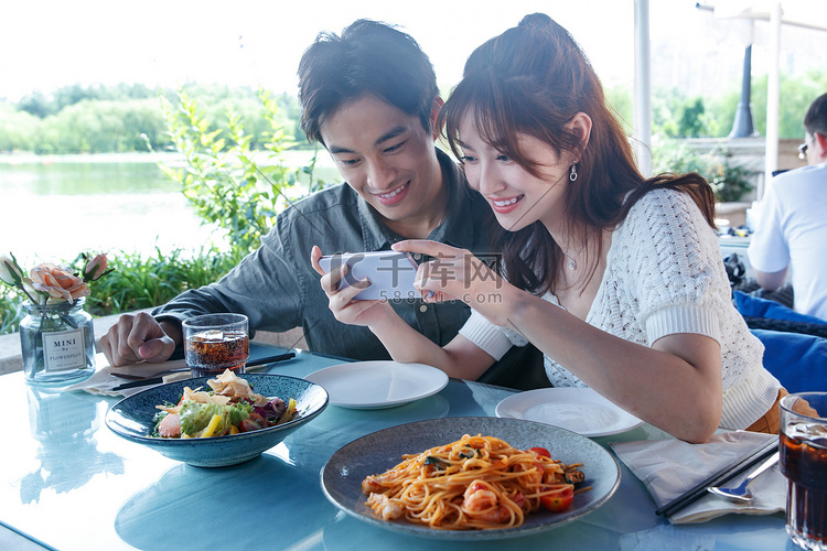 青年情侣在餐厅里用手机拍照