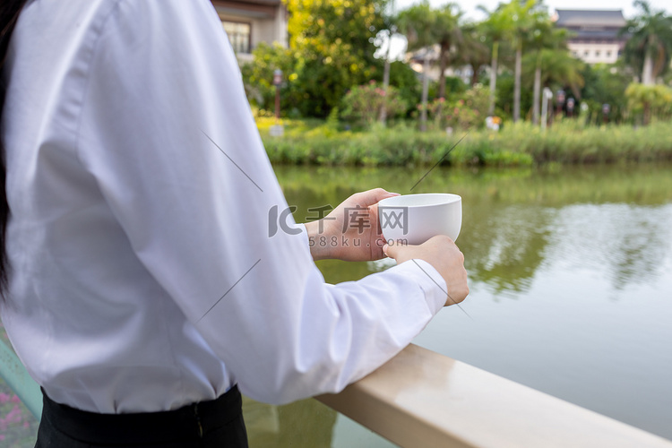 商务下午商务女性湖边拿着咖啡的