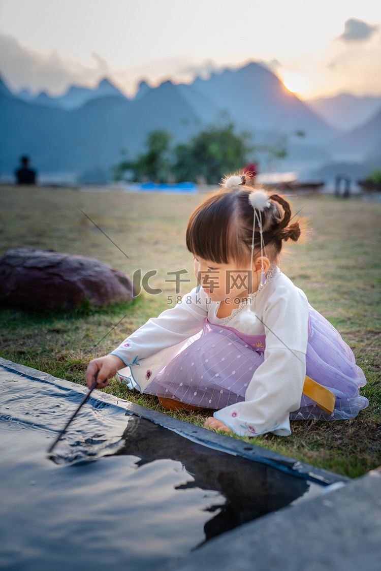 玩水的小女孩夕阳儿童户外半身摄