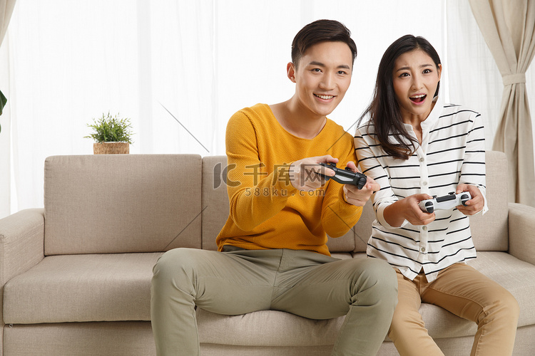 青年情侣坐着沙发上玩游戏
