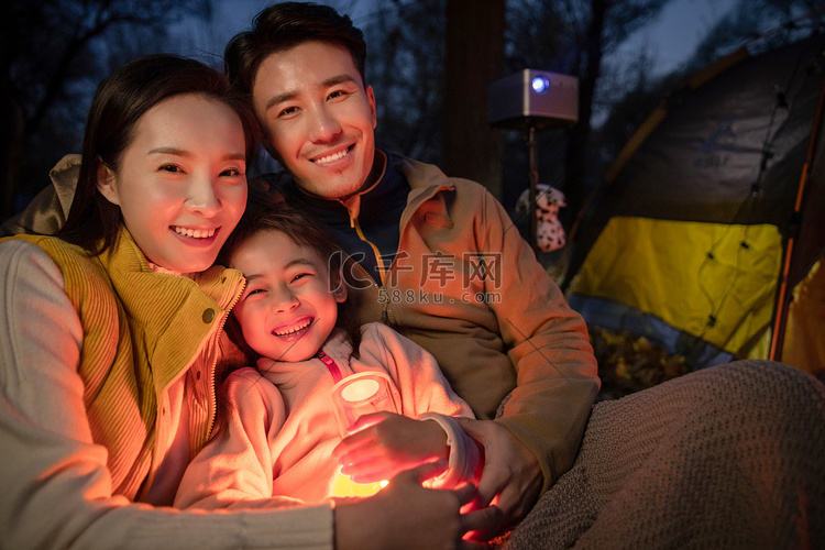 幸福的一家三口夜晚在野外露营