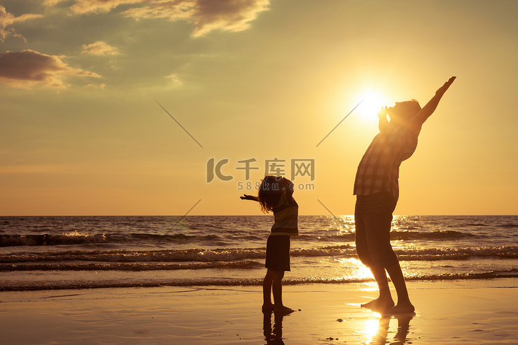 父亲和儿子在日落的时候在海滩上